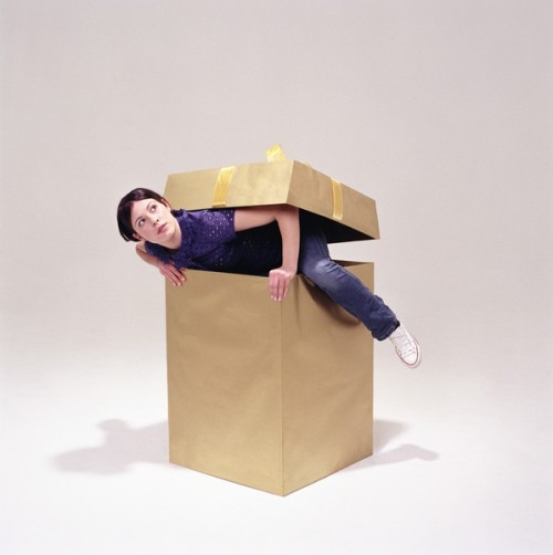 Young woman climbing out of box